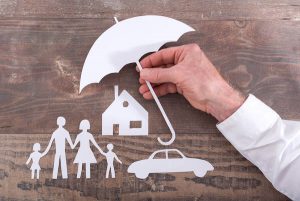 male hand holding an umbrella over a family, their home and car