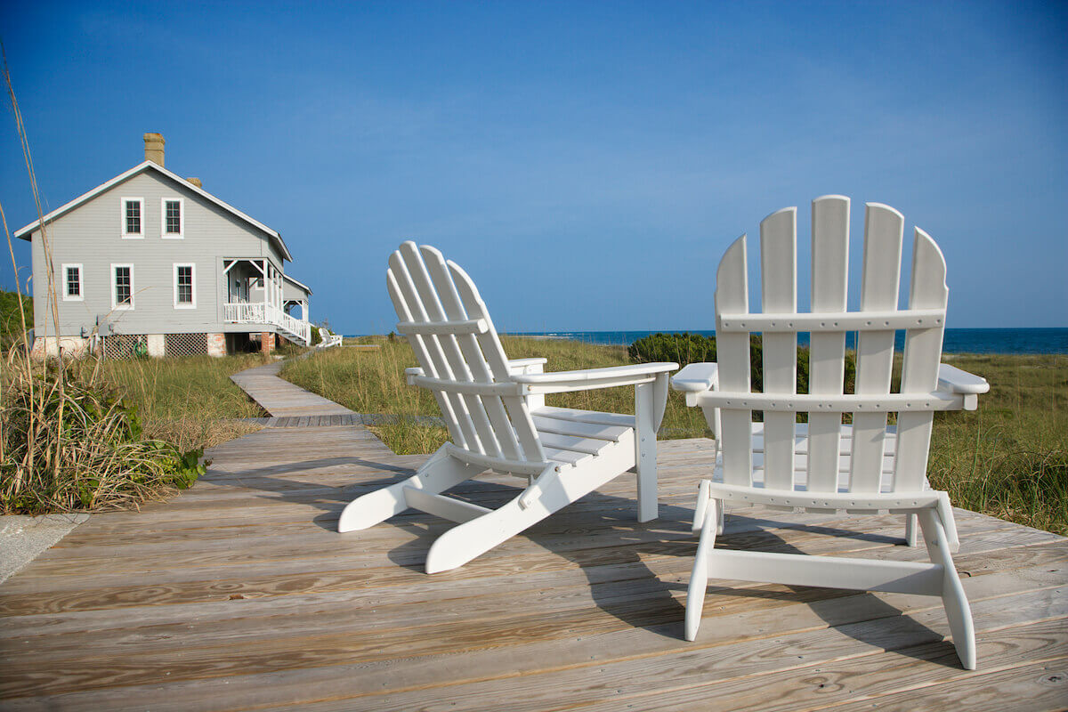 a beach house with a dock and two chairs