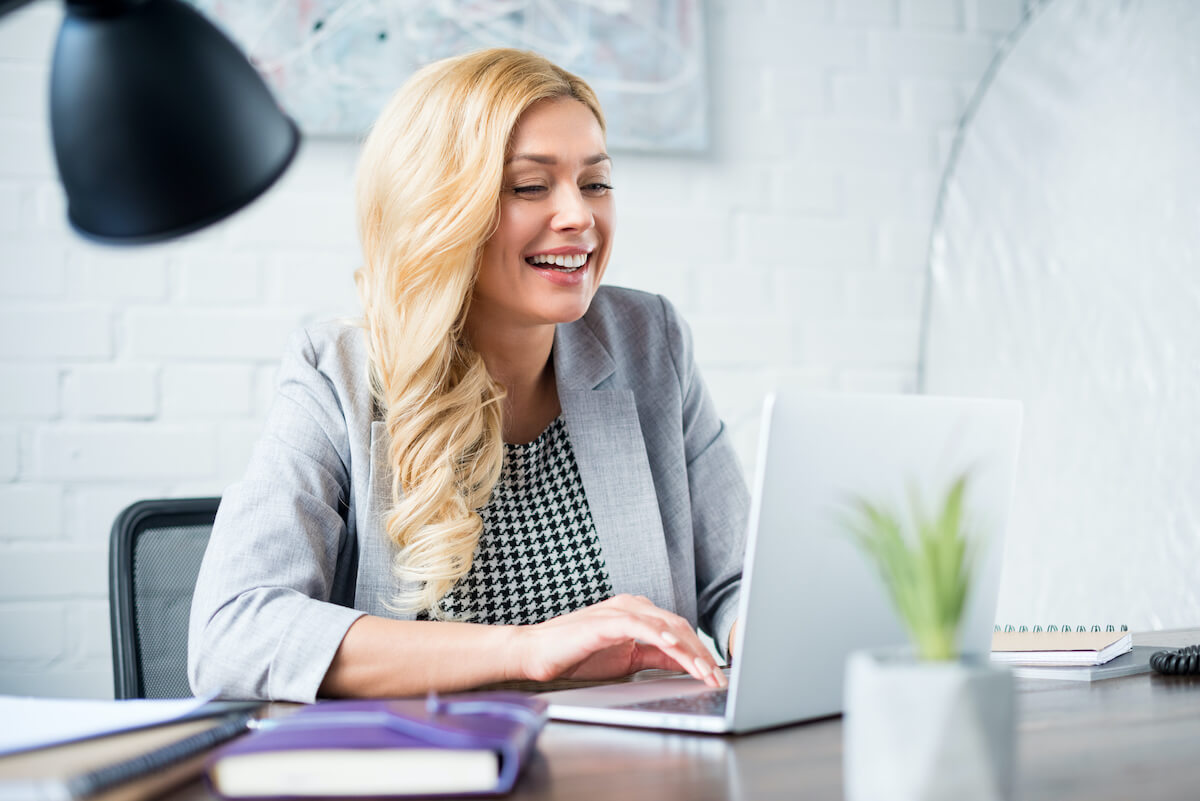 Smiling businesswoman using laptop at work