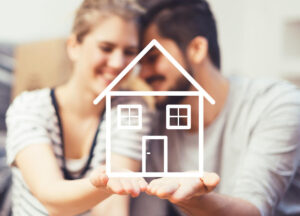 a couple holding the outline of a home in the palm of their hands